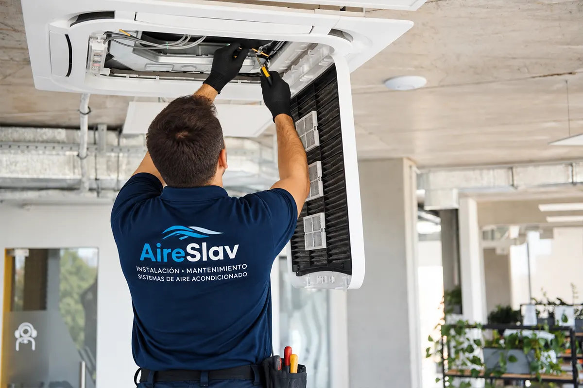 Técnico de AIRESLAV realizando mantenimiento de aire acondicionado en una empresa de Valencia